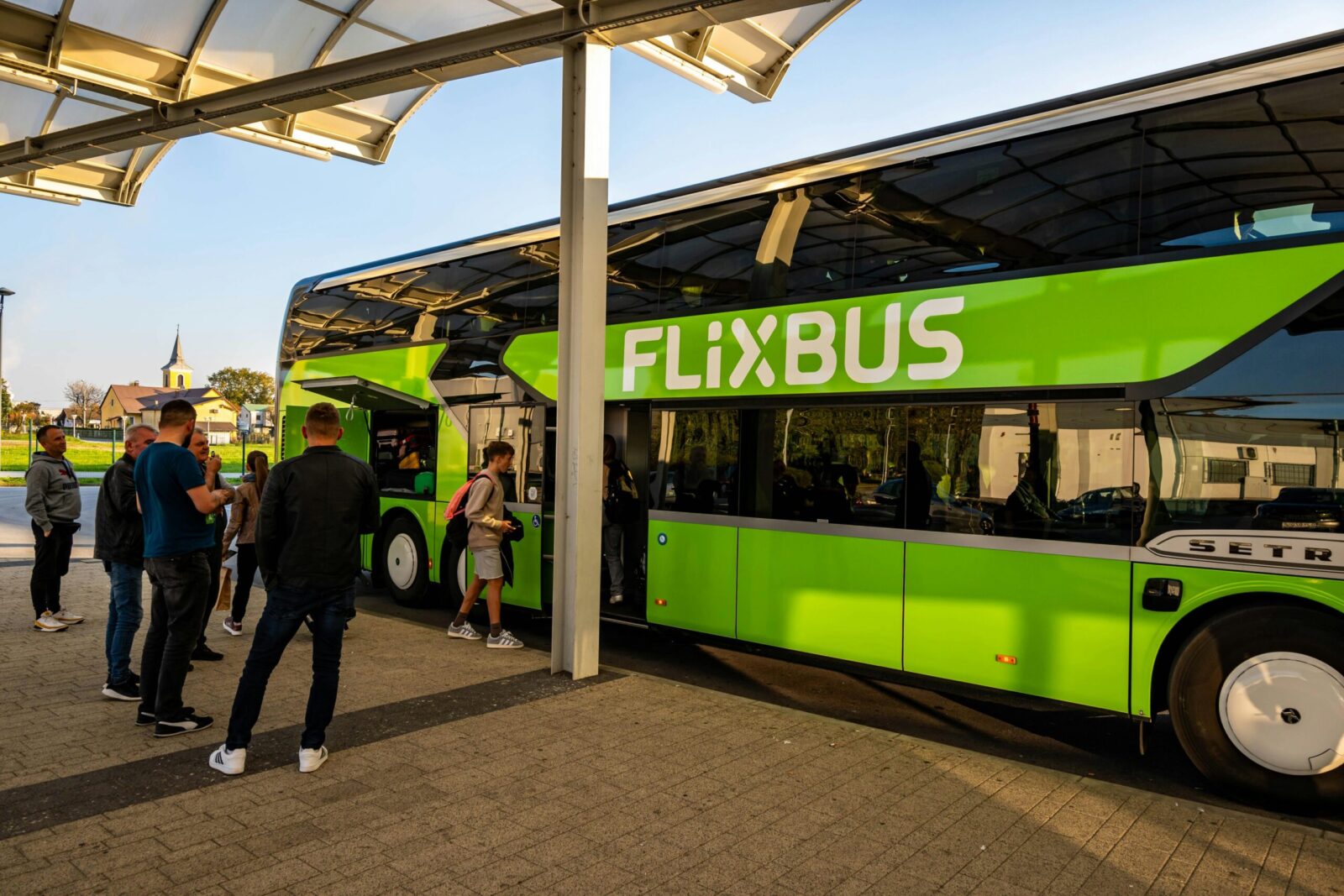 Passengers boarding a green Flixbus at Kutina Bus Station on a sunny day in Croatia.