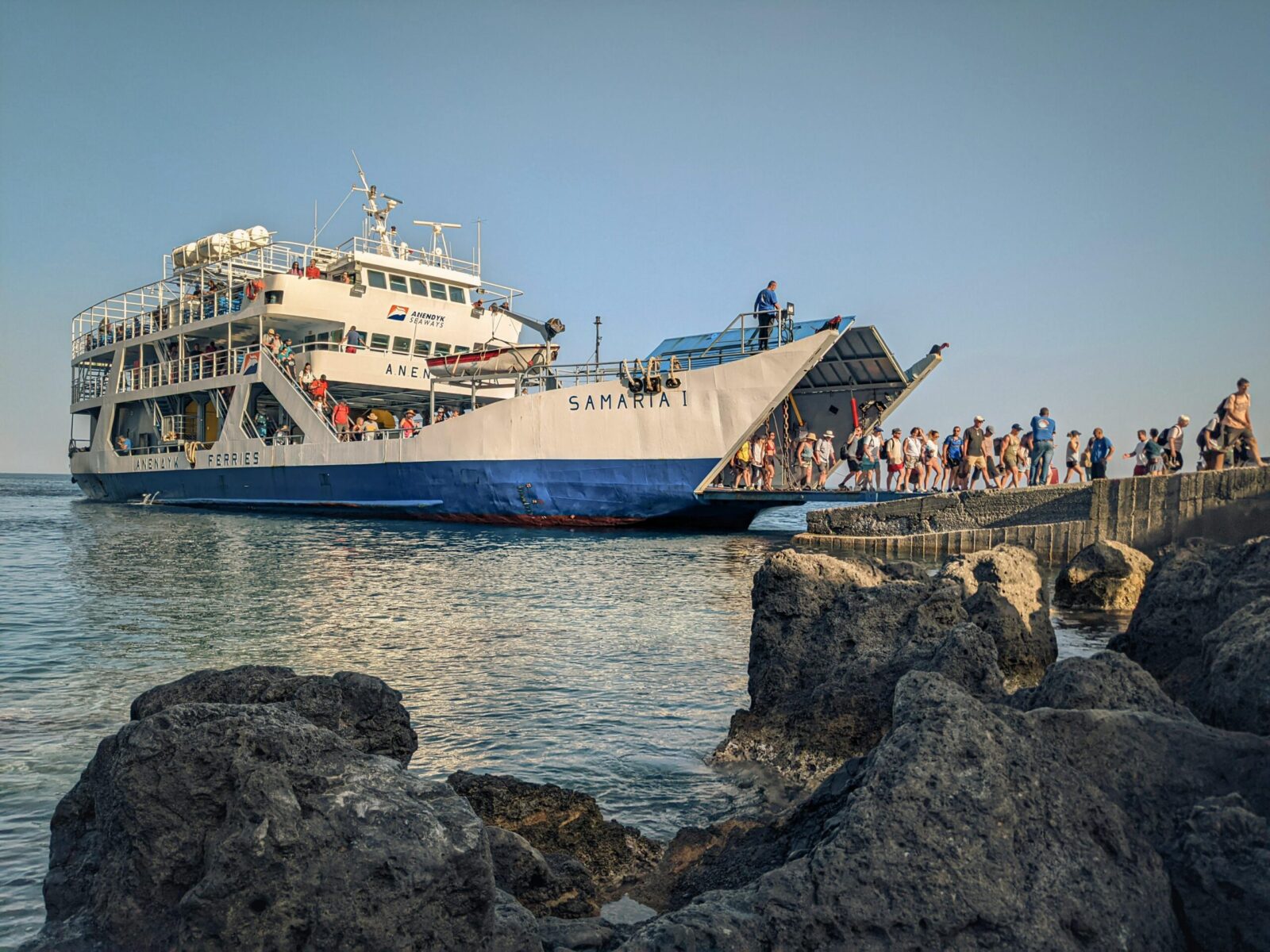 Tourists disembark the Samaria I ferry at a rocky coastline in Crete, Greece during daytime.