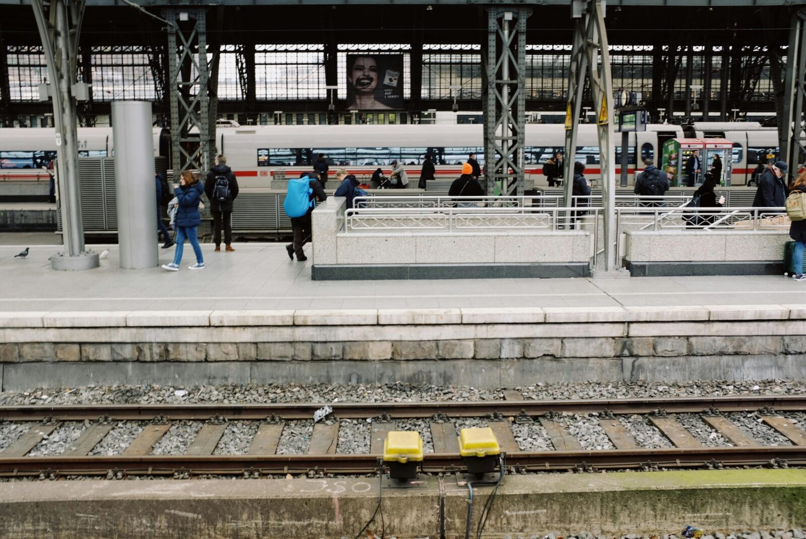 Commuters await trains at a busy urban station platform, showcasing public transportation.